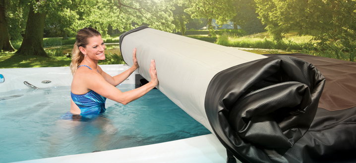 mujer enrollando el sistema de cubierta del eje mientras está dentro de su spa de natación