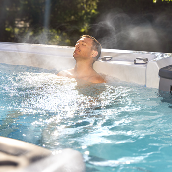 Un hombre que se relaja en el agua, de cuya superficie sale vapor.
