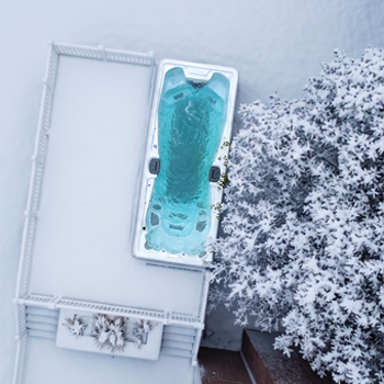 Vista desde un dron de un spa de natación en funcionamiento en invierno, rodeado de nieve.