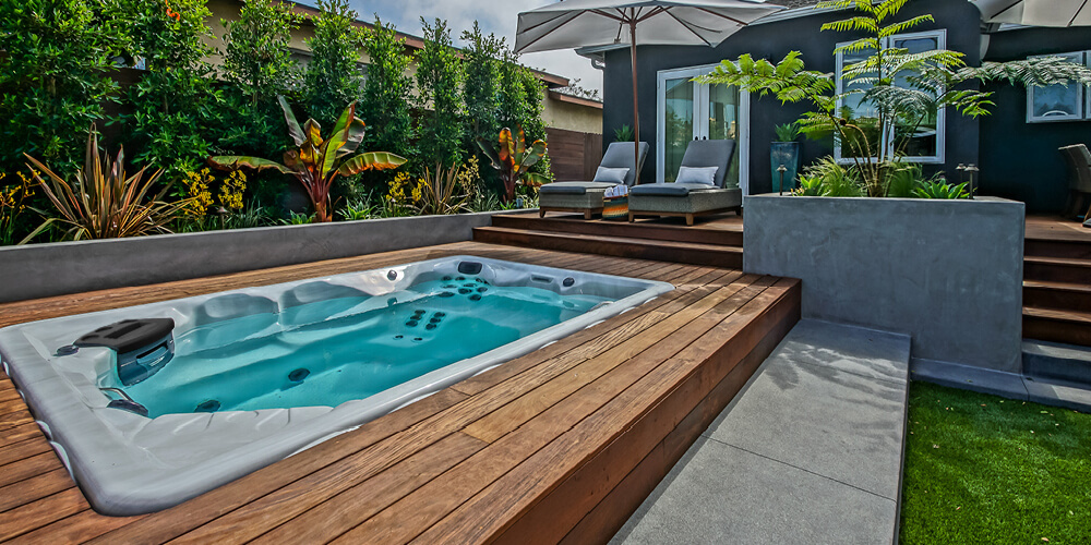 Sombrillas y tumbonas dispuestas alrededor de un spa de natación Therapool.