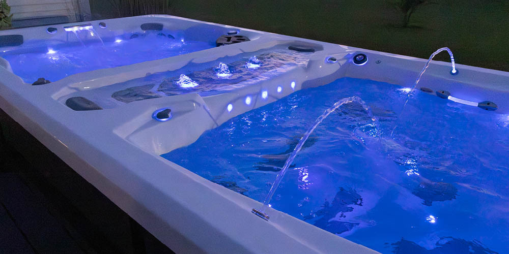 Vista nocturna de un spa de natación con juegos de agua y luces LED encendidas.