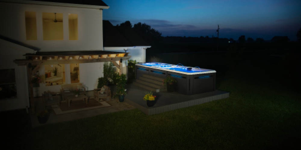 Fotografía nocturna de un spa de natación en un jardín trasero.